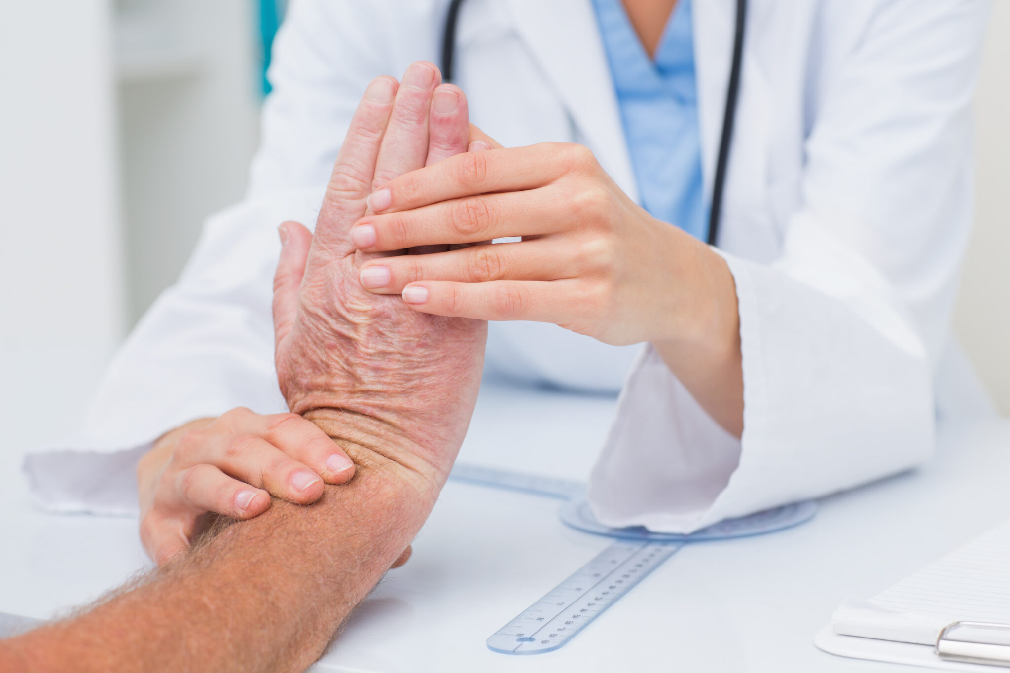 Cropped image of female physiotherapist examining male patients wrist in clinic